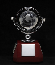 Load image into Gallery viewer, A globe trophy featuring a clear glass globe with an etched world map design, mounted on a polished silver-colored metal frame and supported by a dark red octagonal base with a blank silver plaque.
